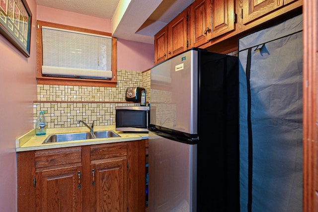 kitchen with stainless steel appliances, a sink, tasteful backsplash, and light countertops