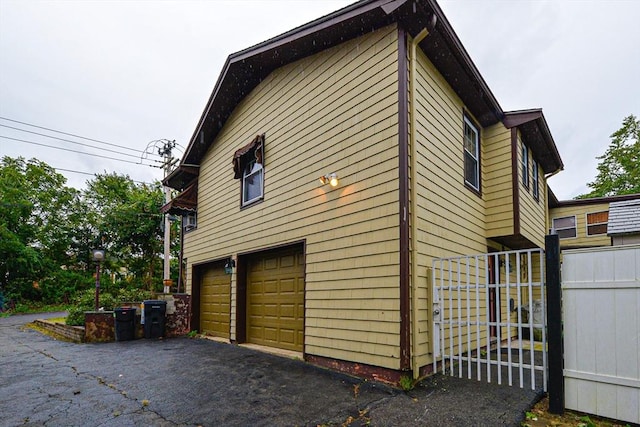view of property exterior with a garage, fence, and driveway