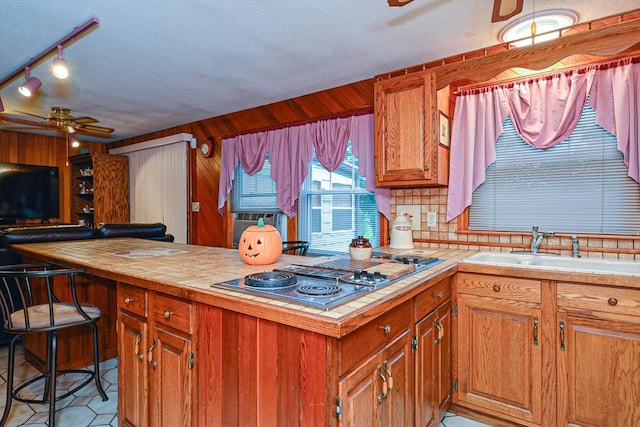 kitchen featuring stainless steel electric cooktop, a ceiling fan, a sink, a textured ceiling, and tile countertops