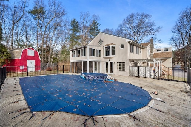 view of swimming pool featuring a sunroom, a patio area, and an outdoor structure