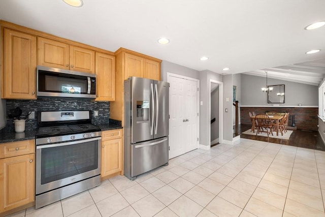 kitchen with dark stone countertops, stainless steel appliances, vaulted ceiling, and an inviting chandelier