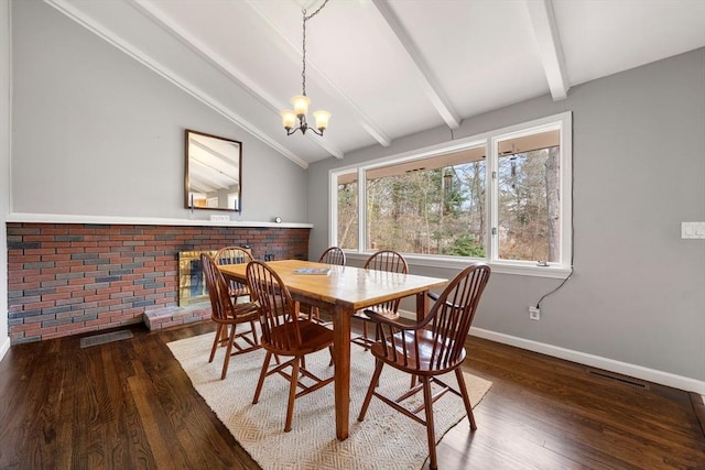 dining area featuring a fireplace, dark hardwood / wood-style flooring, lofted ceiling with beams, and a notable chandelier