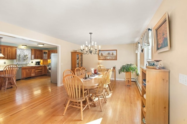 dining room featuring sink, a chandelier, and light hardwood / wood-style flooring