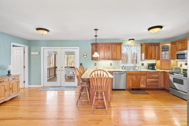 kitchen featuring light hardwood / wood-style flooring, pendant lighting, stainless steel appliances, french doors, and a breakfast bar area