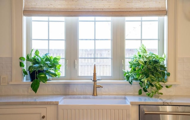 room details featuring decorative backsplash, white cabinetry, a sink, and dishwasher