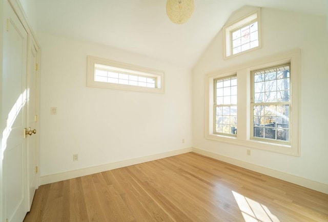 unfurnished room featuring lofted ceiling, baseboards, and wood finished floors