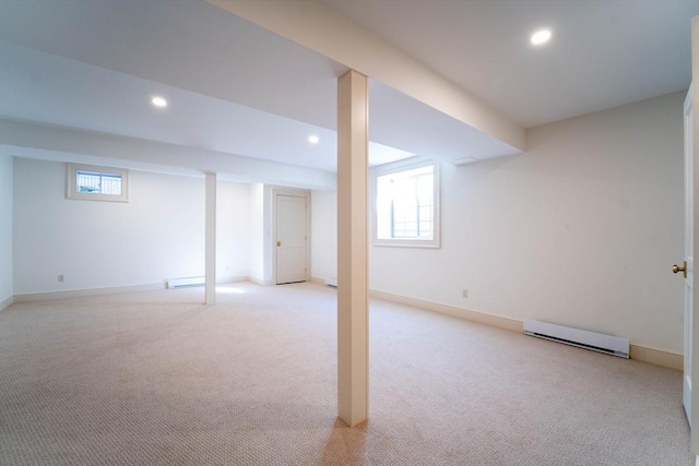 basement with a baseboard heating unit, recessed lighting, light colored carpet, and plenty of natural light