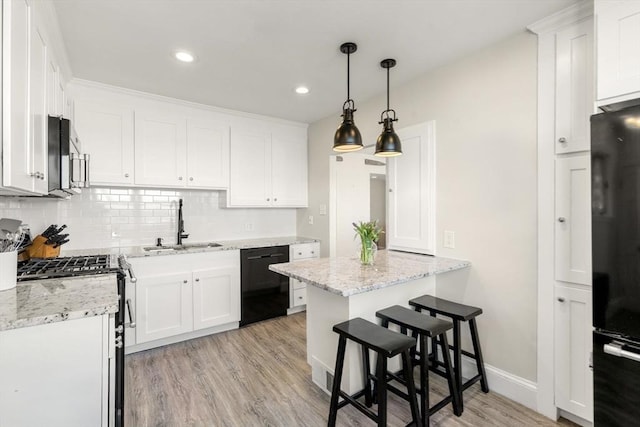 kitchen with black appliances, a sink, light wood-type flooring, tasteful backsplash, and white cabinetry