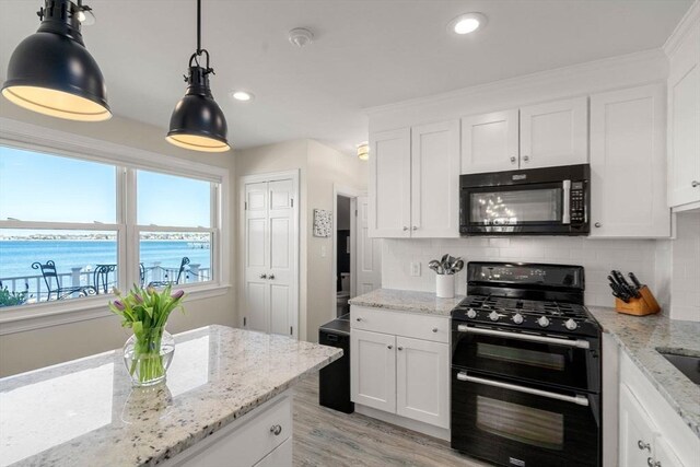 kitchen with range with two ovens, tasteful backsplash, white cabinetry, light wood-style floors, and pendant lighting