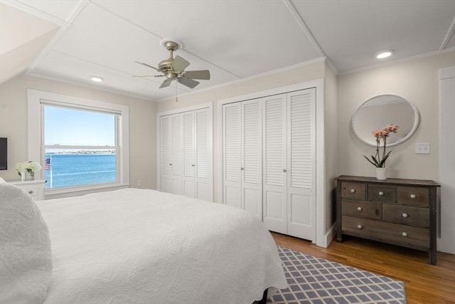 bedroom featuring wood finished floors, multiple closets, ornamental molding, recessed lighting, and ceiling fan