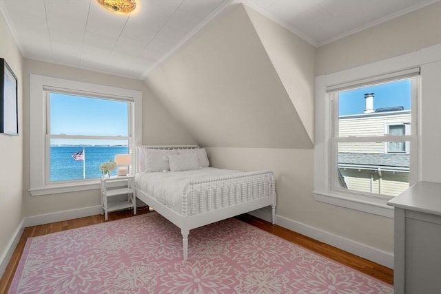 bedroom featuring crown molding, wood finished floors, baseboards, a water view, and vaulted ceiling