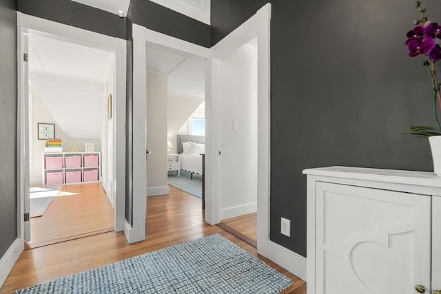 hall with light wood-style floors and baseboards