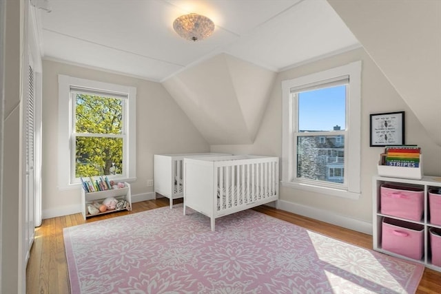 bedroom with multiple windows, lofted ceiling, wood finished floors, and baseboards