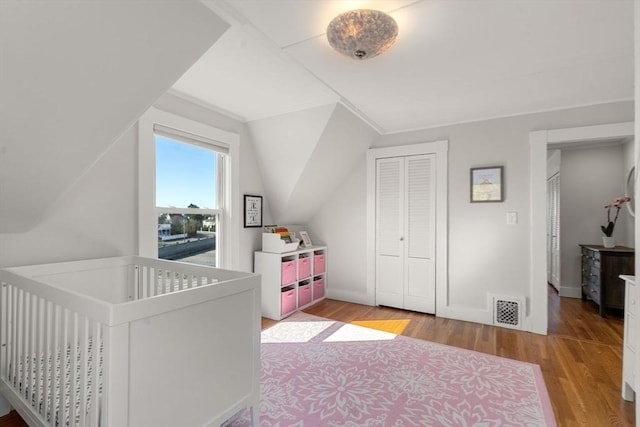 bedroom with wood finished floors, a closet, and baseboards