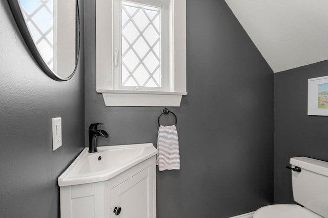 bathroom featuring toilet, lofted ceiling, and vanity
