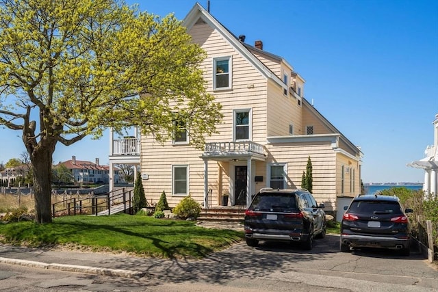 view of front of home featuring a chimney and a balcony