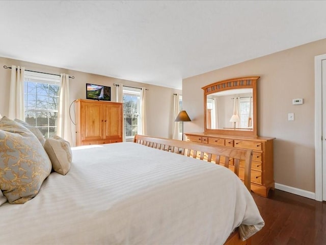 bedroom featuring multiple windows, baseboards, and dark wood-style flooring