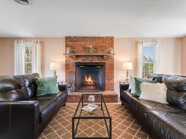 living area featuring a brick fireplace, visible vents, and a wealth of natural light