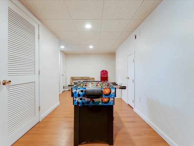 rec room with a drop ceiling, light wood-type flooring, and baseboards