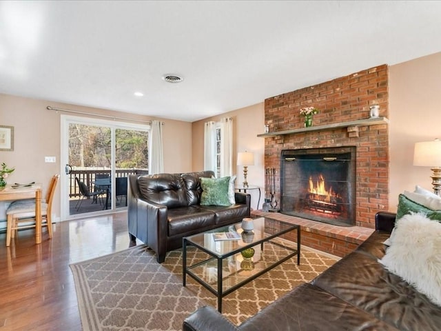 living room featuring wood finished floors, a fireplace, and visible vents