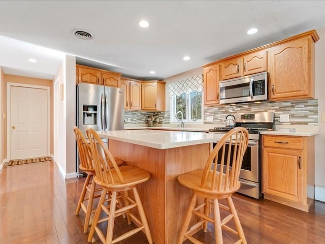 kitchen with a kitchen breakfast bar, dark wood-style floors, visible vents, and stainless steel appliances