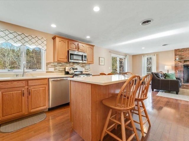 kitchen with a sink, backsplash, a center island, appliances with stainless steel finishes, and a breakfast bar area