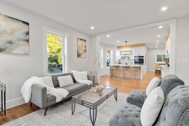 living room featuring light wood finished floors, recessed lighting, and baseboards