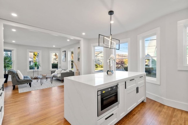 kitchen with plenty of natural light, white cabinetry, light wood-type flooring, and light countertops