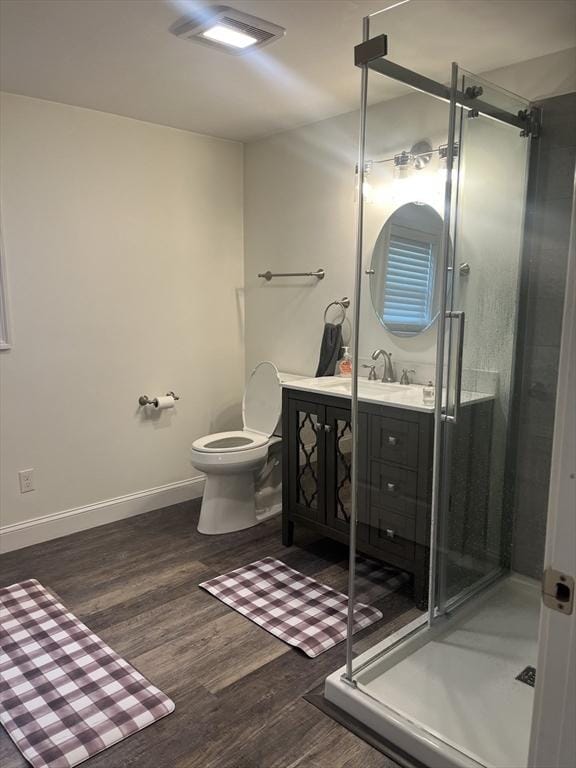 bathroom featuring wood finished floors, a shower stall, visible vents, and vanity