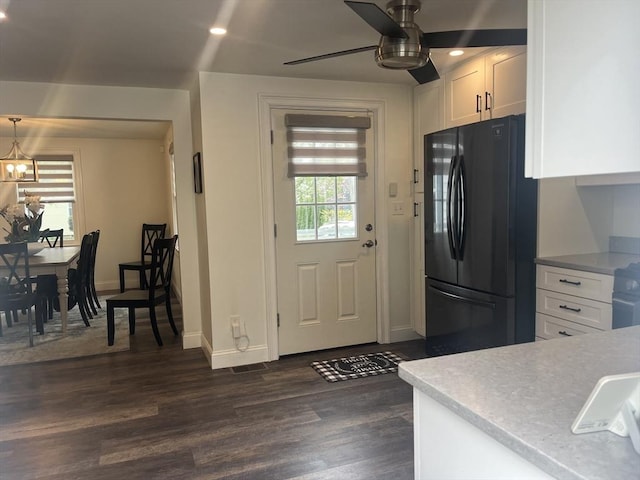 kitchen featuring dark wood-style flooring, white cabinetry, freestanding refrigerator, and ceiling fan with notable chandelier