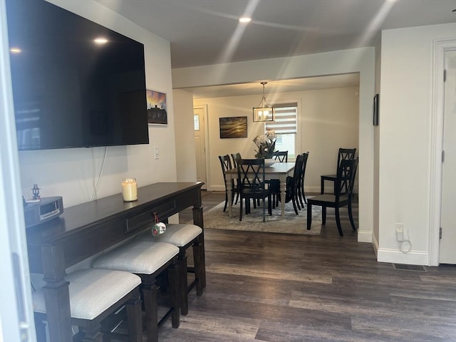 dining room with visible vents, dark wood-style flooring, a chandelier, and baseboards