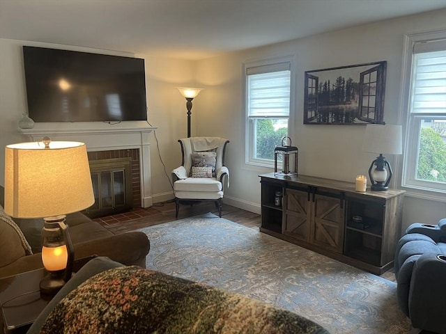 living area featuring baseboards, wood finished floors, and a fireplace