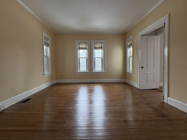 spare room with dark wood finished floors, visible vents, crown molding, and baseboards