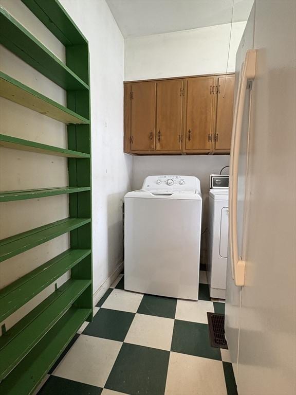 clothes washing area with cabinet space, washing machine and dryer, and light floors