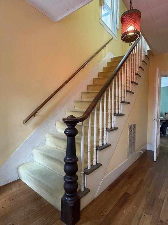 stairs featuring visible vents, baseboards, and hardwood / wood-style floors