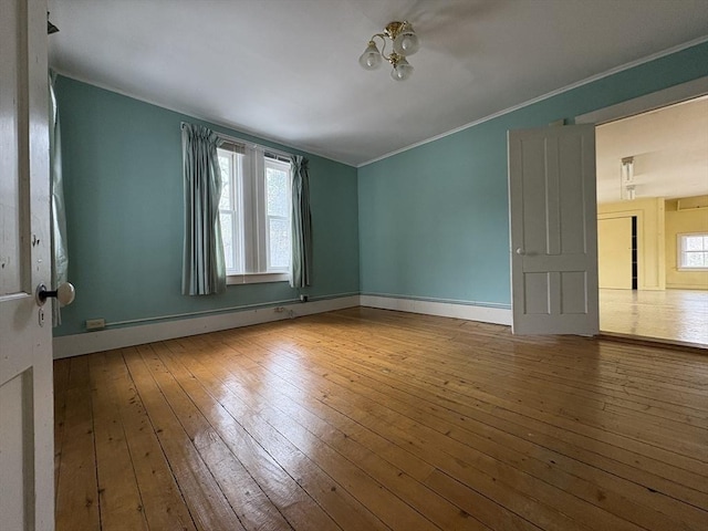 empty room with plenty of natural light, ornamental molding, and hardwood / wood-style floors