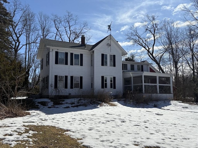 view of front of house with a chimney and a sunroom