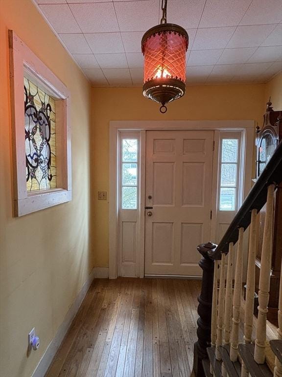 entryway featuring a paneled ceiling, stairway, baseboards, and hardwood / wood-style flooring