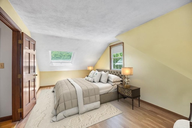 19 K St, Weymouth, MA 02189 - bedroom with light wood-style flooring, a skylight, lofted ceiling, baseboards, and a textured ceiling