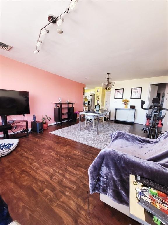 living room with wood-type flooring, rail lighting, and a chandelier