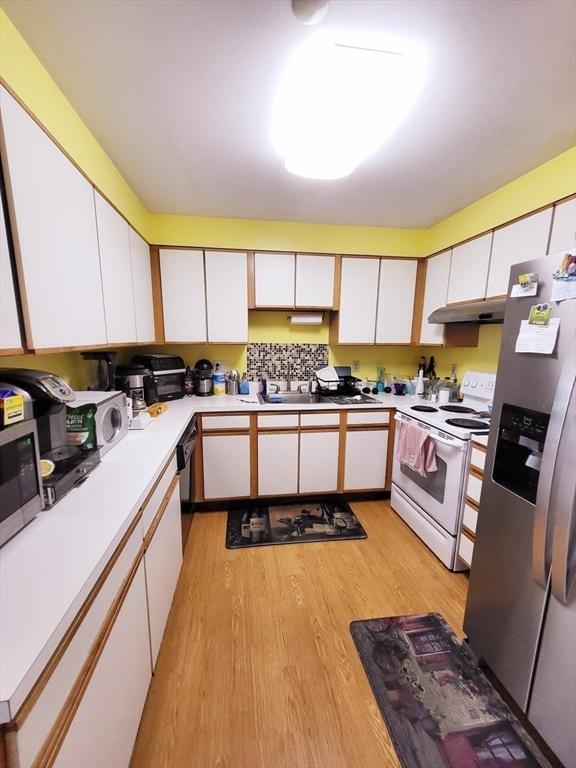 kitchen with white cabinetry, sink, stainless steel appliances, and light hardwood / wood-style floors