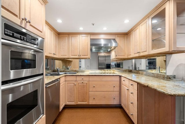 kitchen with light brown cabinets, wall chimney range hood, and stainless steel appliances