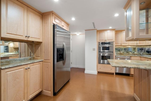 kitchen with light stone counters, stainless steel appliances, and light brown cabinetry