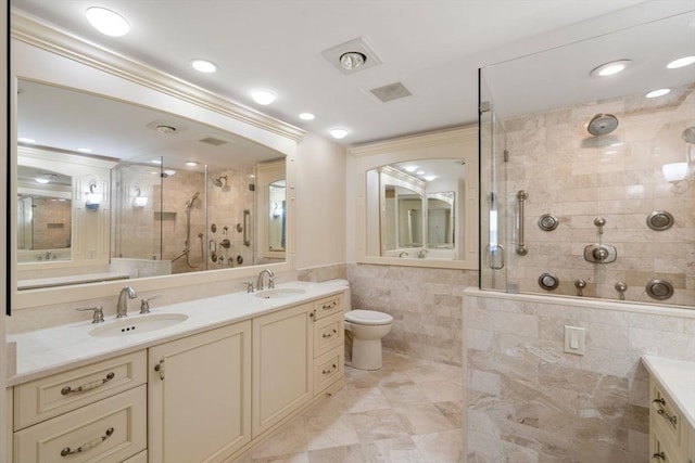 bathroom featuring vanity, toilet, a shower with shower door, and tile walls