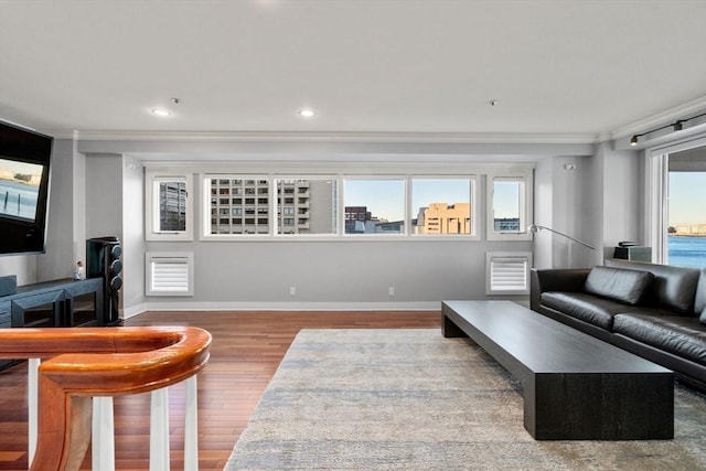 living room with a wealth of natural light, wood-type flooring, and ornamental molding