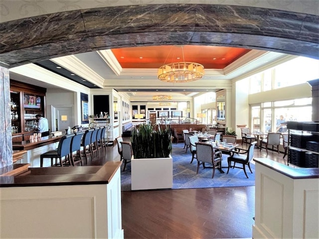 dining area with dark hardwood / wood-style flooring, a raised ceiling, crown molding, and a notable chandelier