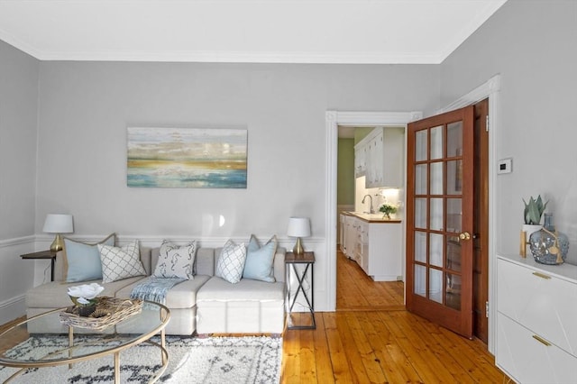 living room featuring french doors, light wood-type flooring, and crown molding