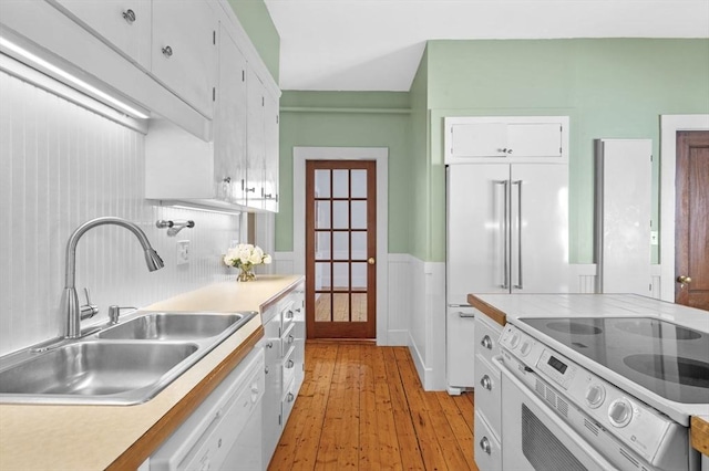 kitchen with sink, white cabinets, white appliances, and light hardwood / wood-style flooring