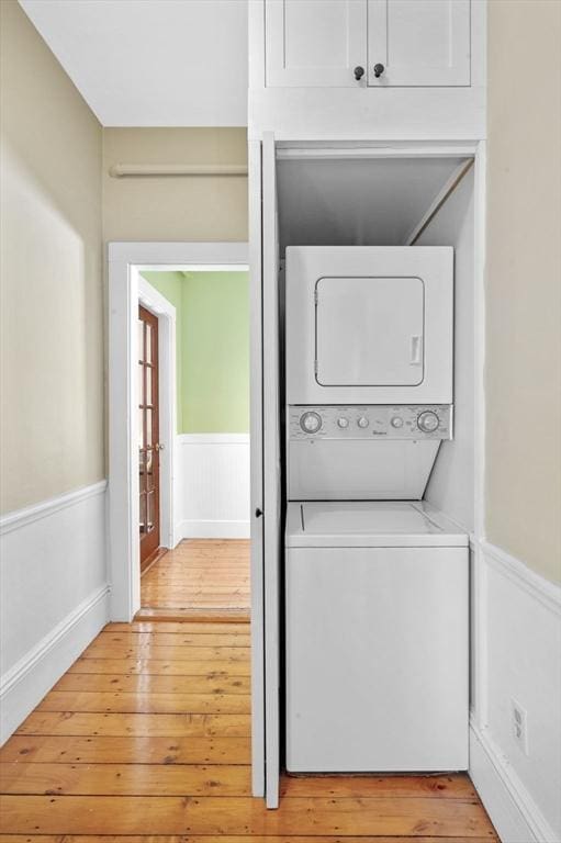 washroom featuring light hardwood / wood-style floors and stacked washer and clothes dryer