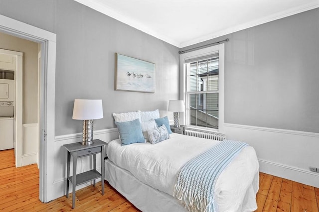 bedroom featuring radiator heating unit, light hardwood / wood-style flooring, and ornamental molding